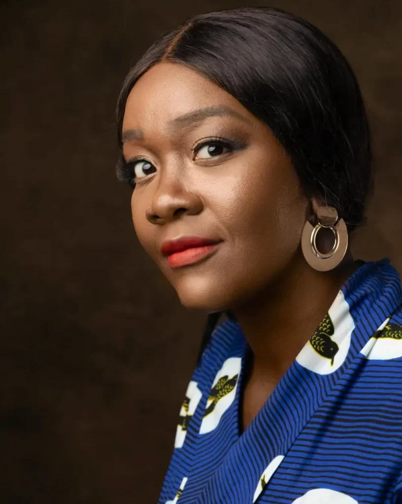 Portrait of Belocine Musolo wearing bold earrings and a patterned wrap dress