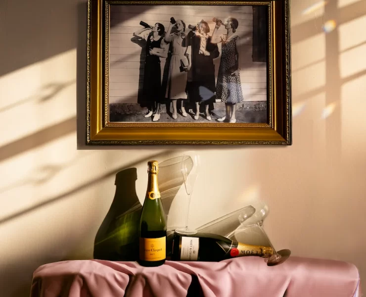 Framed vintage photo of women drinking champagne, with Veuve Clicquot and Moët bottles and glassware on a pink-draped table
