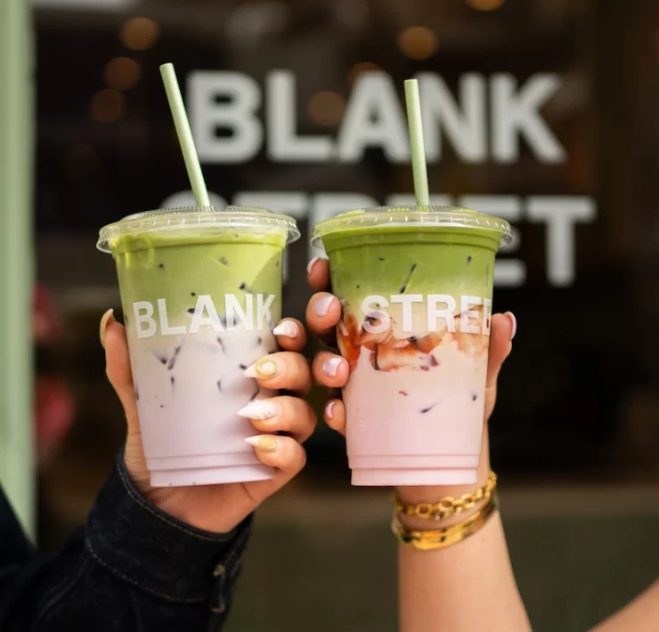 Two hands holding iced matcha drinks from Blank Street Glasgow with branded cups