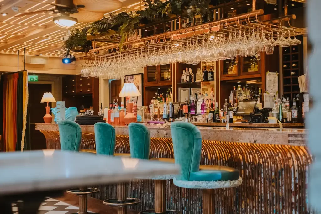 Copper Blossom bar in Edinburgh featuring plush teal stools, rose gold finishes, and a colourful cocktail display.