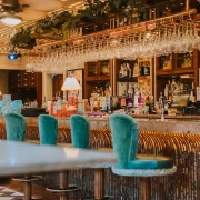 Copper Blossom bar in Edinburgh featuring plush teal stools, rose gold finishes, and a colourful cocktail display.