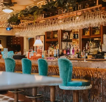 Copper Blossom bar in Edinburgh featuring plush teal stools, rose gold finishes, and a colourful cocktail display.