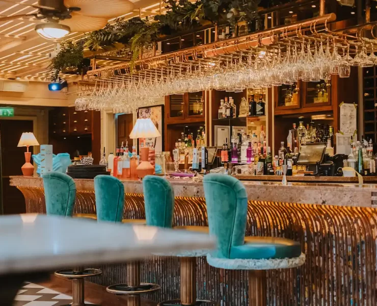 Copper Blossom bar in Edinburgh featuring plush teal stools, rose gold finishes, and a colourful cocktail display.