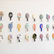 Wall display of colourful, artist-designed table tennis paddles at the TOPSP!N exhibition in Glasgow