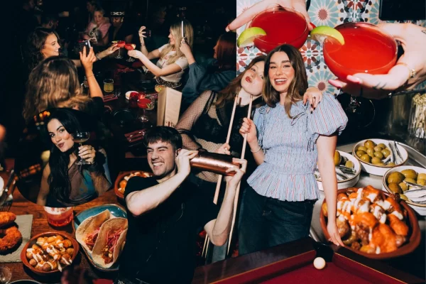 A group of young people enjoying cocktails, Spanish tapas, and socialising at Rioja Glasgow during a lively supper club event.