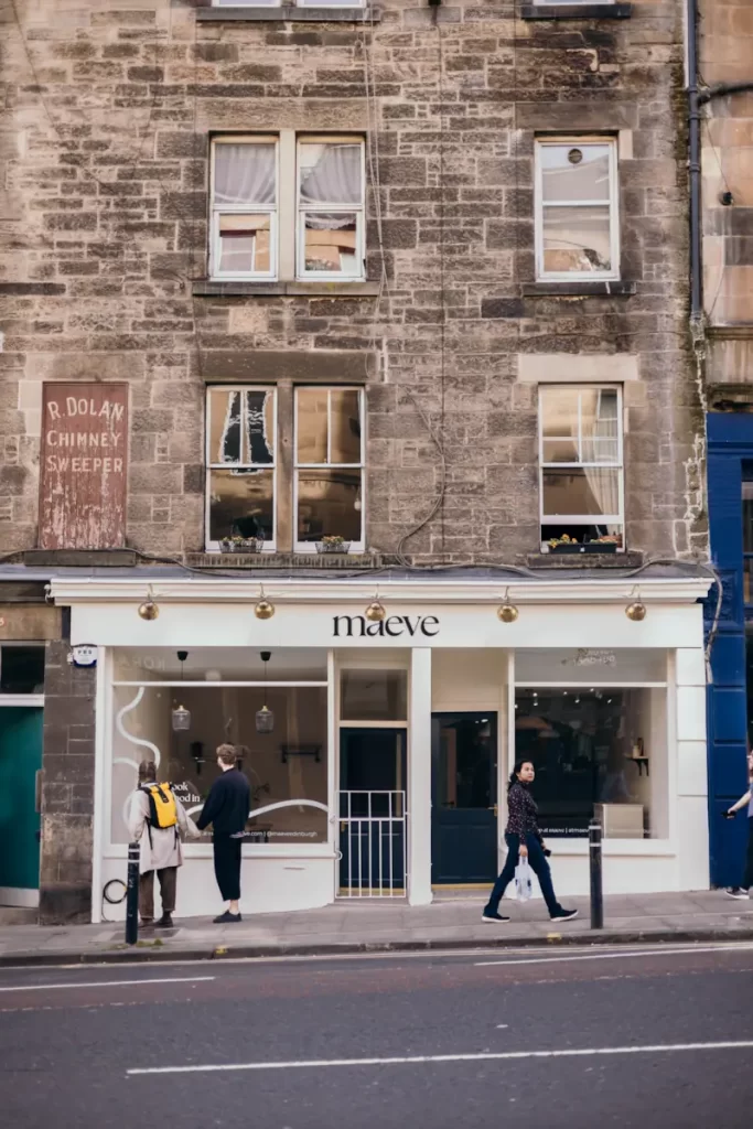 Front of maeve Pilates studio in Leith, Edinburgh, with people walking by the shopfront on a historic city street.