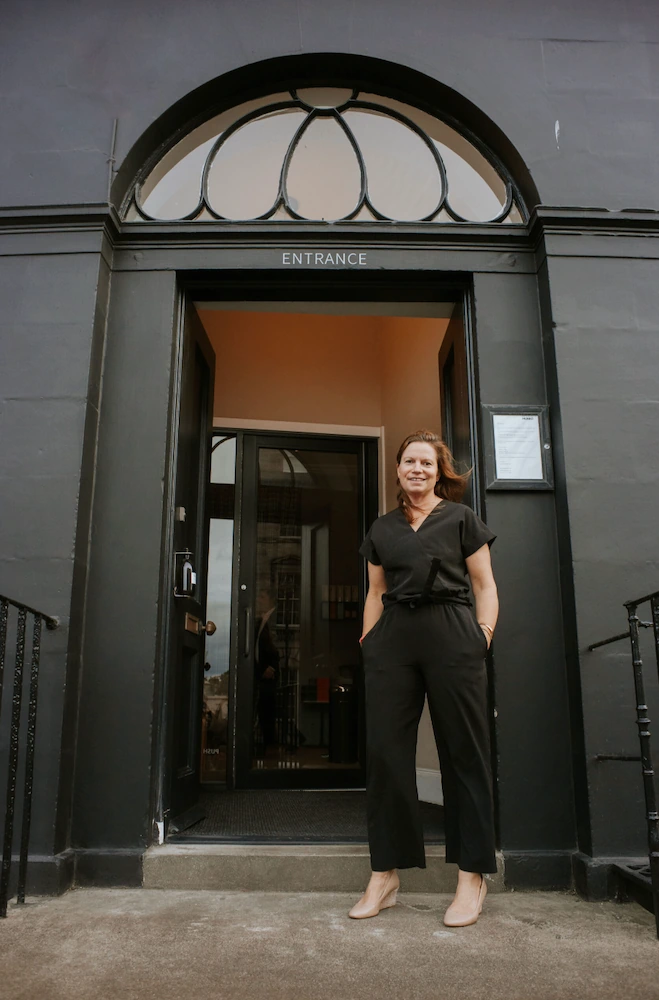 Laura Thomas stands outside the entrance to Moleta Munro in a black jumpsuit, hands in pockets ahead of her exclusive candle-making workshop in Edinburgh.