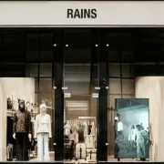 Exterior of the Rains store on Ingram Street, Glasgow, with modern window displays and mannequins in rainwear.