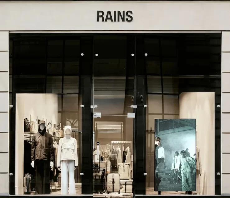 Exterior of the Rains store on Ingram Street, Glasgow, with modern window displays and mannequins in rainwear.