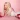 Olivia Raine Atwood lying on a pink background, smiling while holding a red vintage telephone, with another red phone beside her