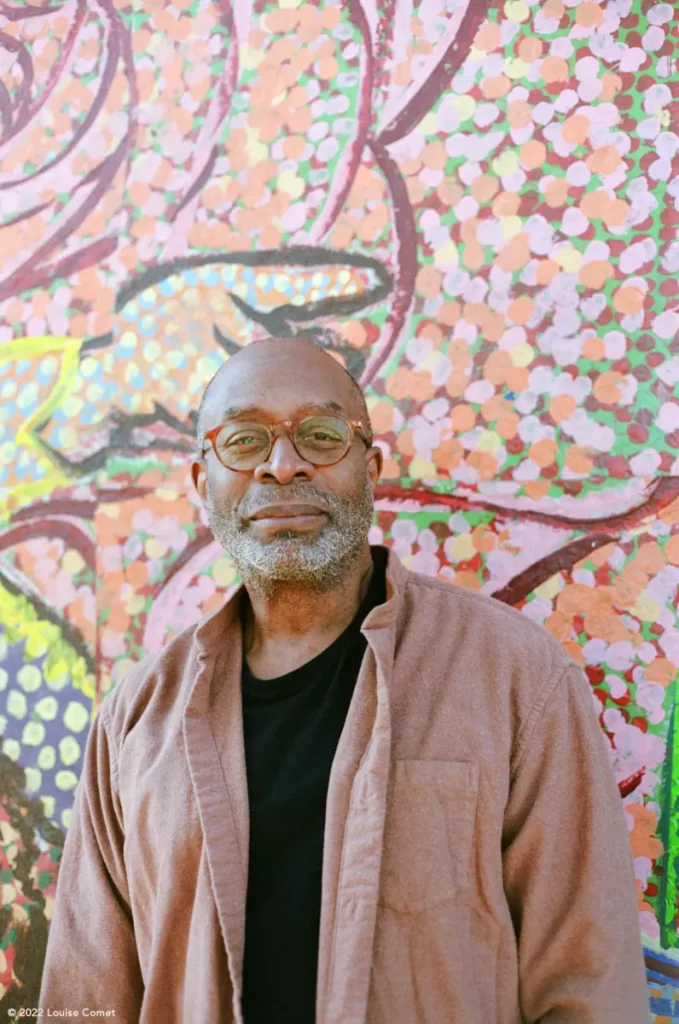 Brian Jackson smiling in front of a colourful mural