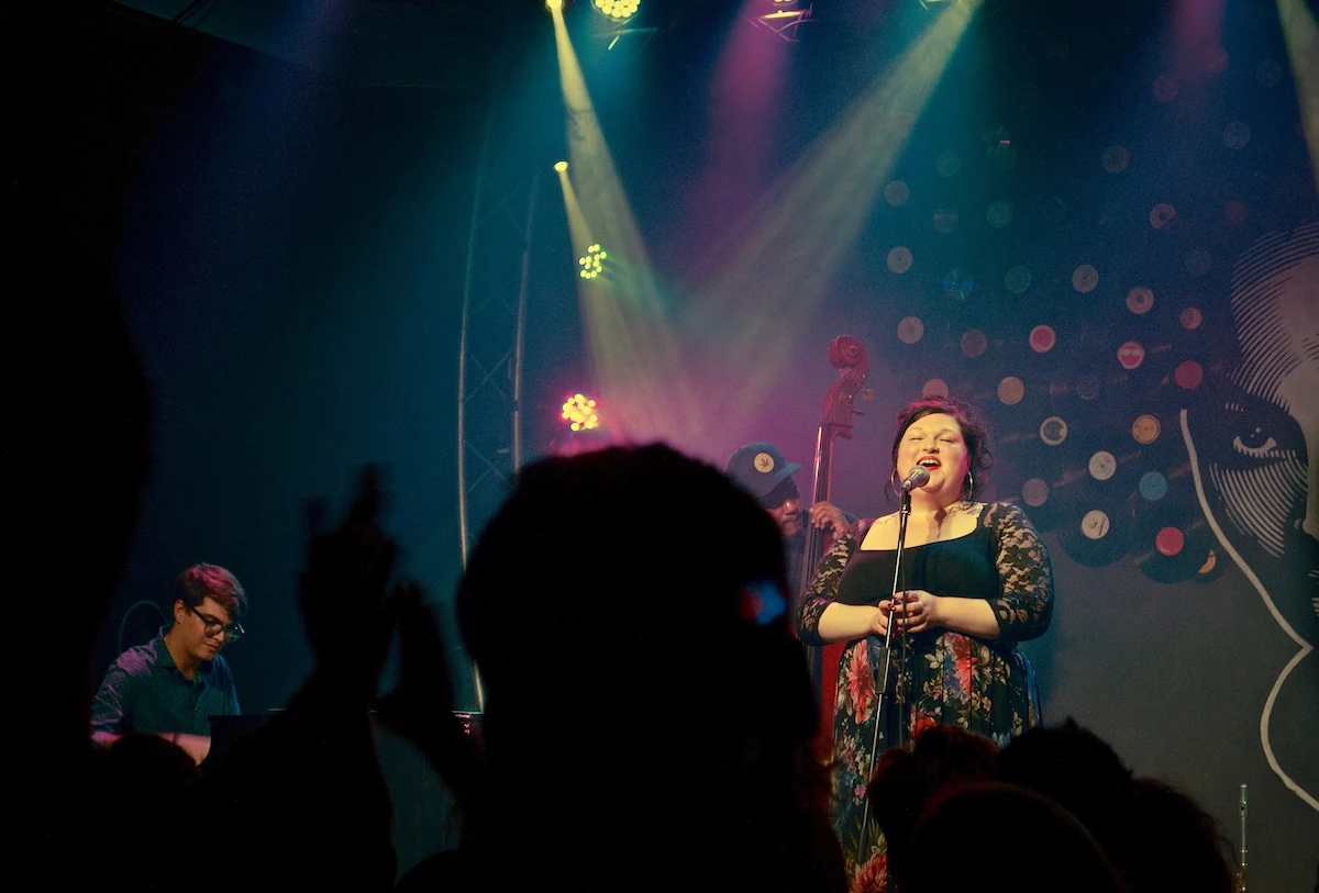 Marianne singing on stage under warm lighting with jazz band behind her