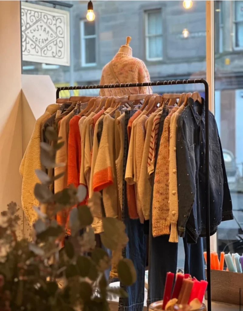 Rail of colourful knitwear and denim inside an Edinburgh indie boutique.