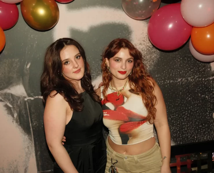 Ellie Devlin and Gaia Ragone, co-founders of The Sapphic Space, posing under colourful balloons at a Pride-themed event in Glasgow