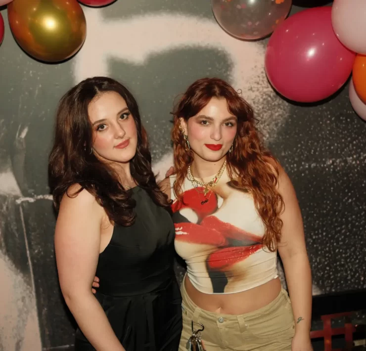 Ellie Devlin and Gaia Ragone, co-founders of The Sapphic Space, posing under colourful balloons at a Pride-themed event in Glasgow