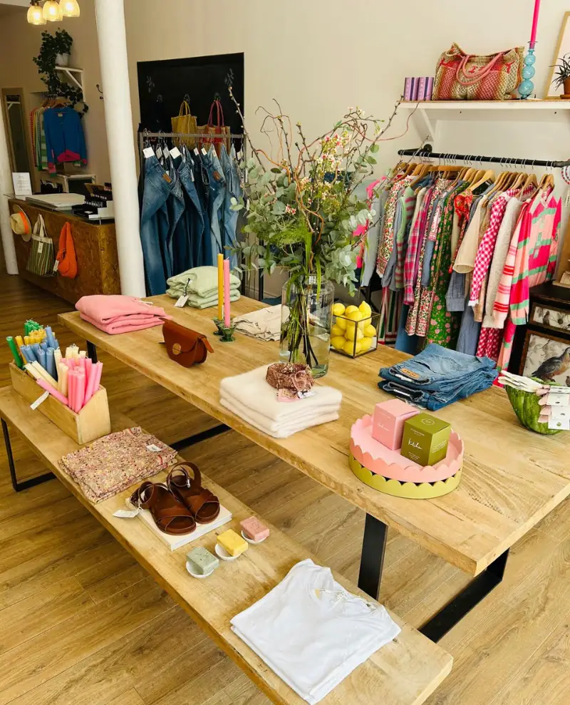 Bright shop interior with colourful rails, denim display and wooden tables.
