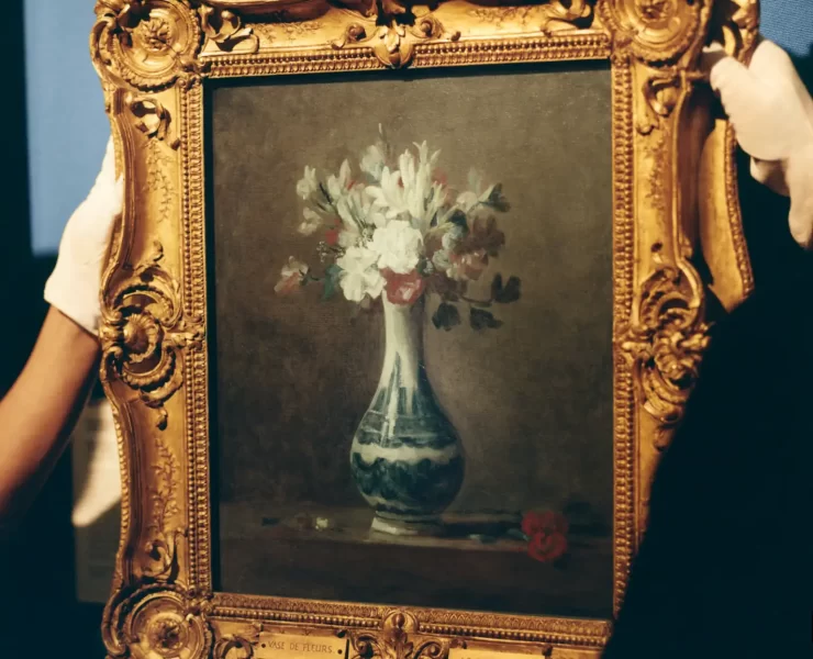A framed painting of a vase of flowers by Jean-Baptiste Siméon Chardin being carefully rehung at the National Galleries Scotland after its feature in Dior’s SS26 menswear show.
