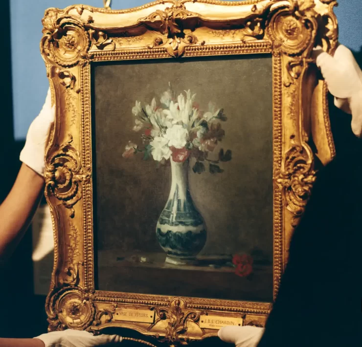 A framed painting of a vase of flowers by Jean-Baptiste Siméon Chardin being carefully rehung at the National Galleries Scotland after its feature in Dior’s SS26 menswear show.