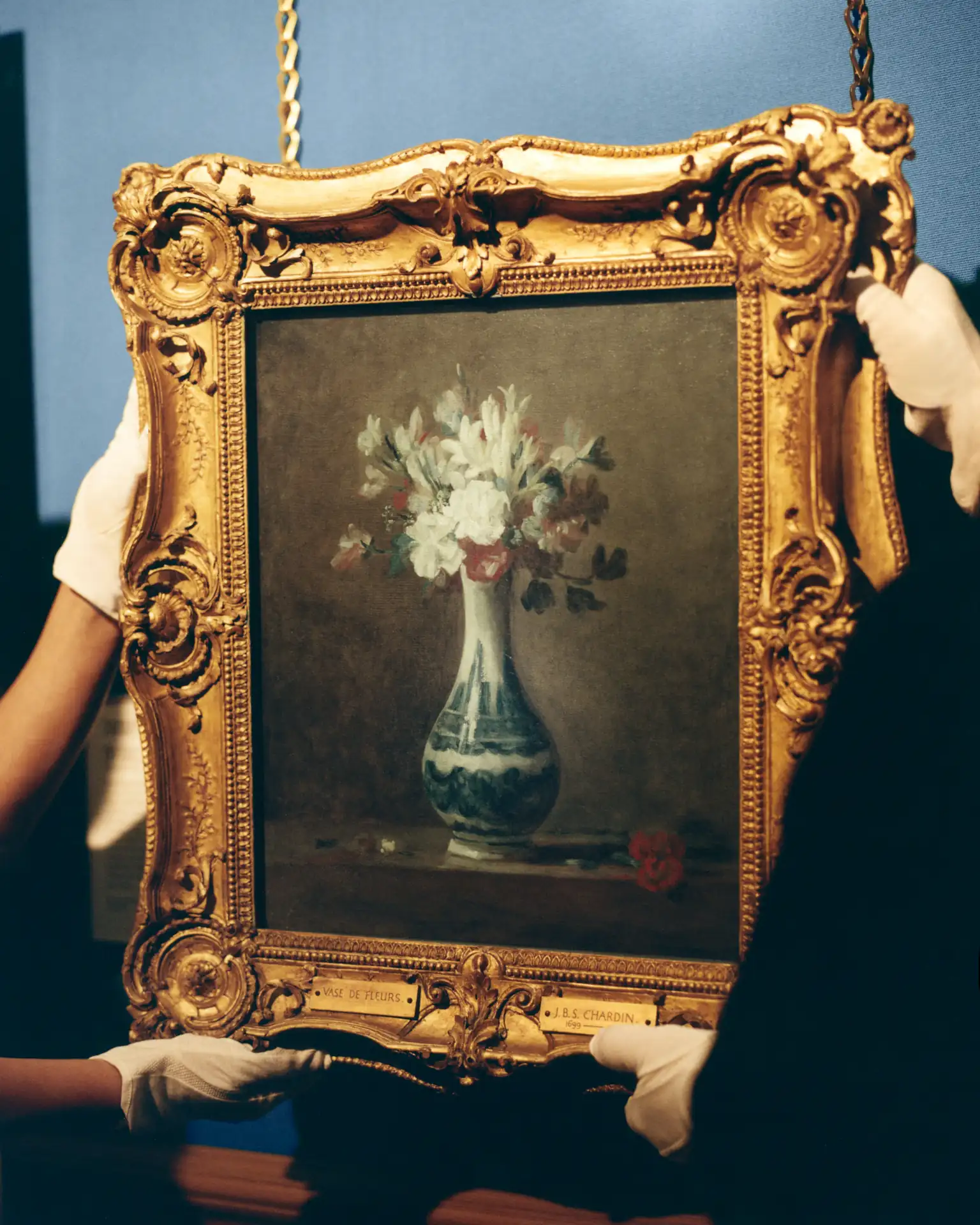 A framed painting of a vase of flowers by Jean-Baptiste Siméon Chardin being carefully rehung at the National Galleries Scotland after its feature in Dior’s SS26 menswear show.