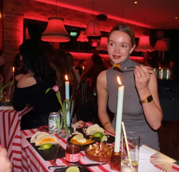 Candlelit table with patatas bravas, paella, tacos and lime wedges.