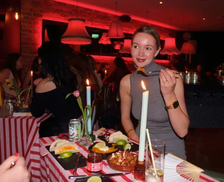Candlelit table with patatas bravas, paella, tacos and lime wedges.