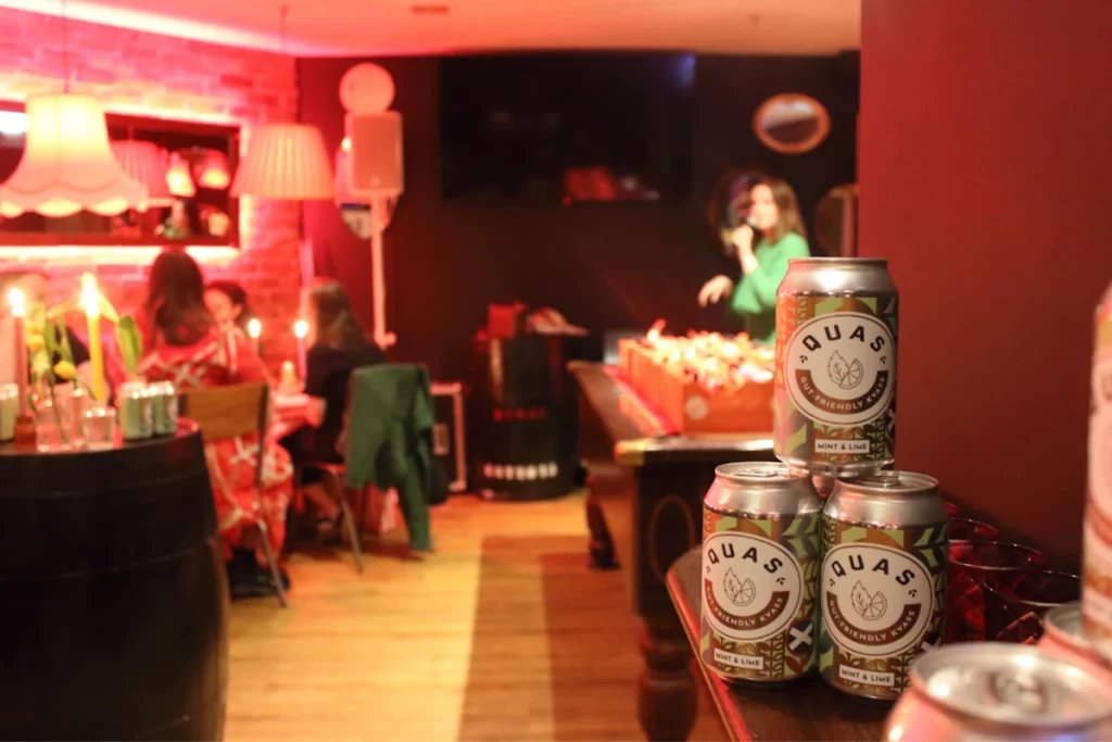 Cans of Quas Mint & Lime soda stacked on a table in the event space.