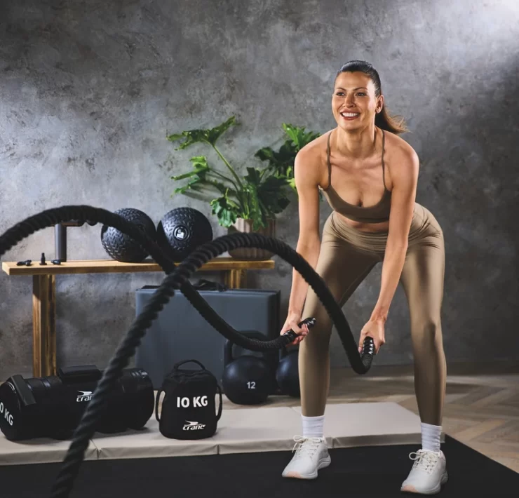 Woman training with Aldi Crane 12m battle ropes at home gym.