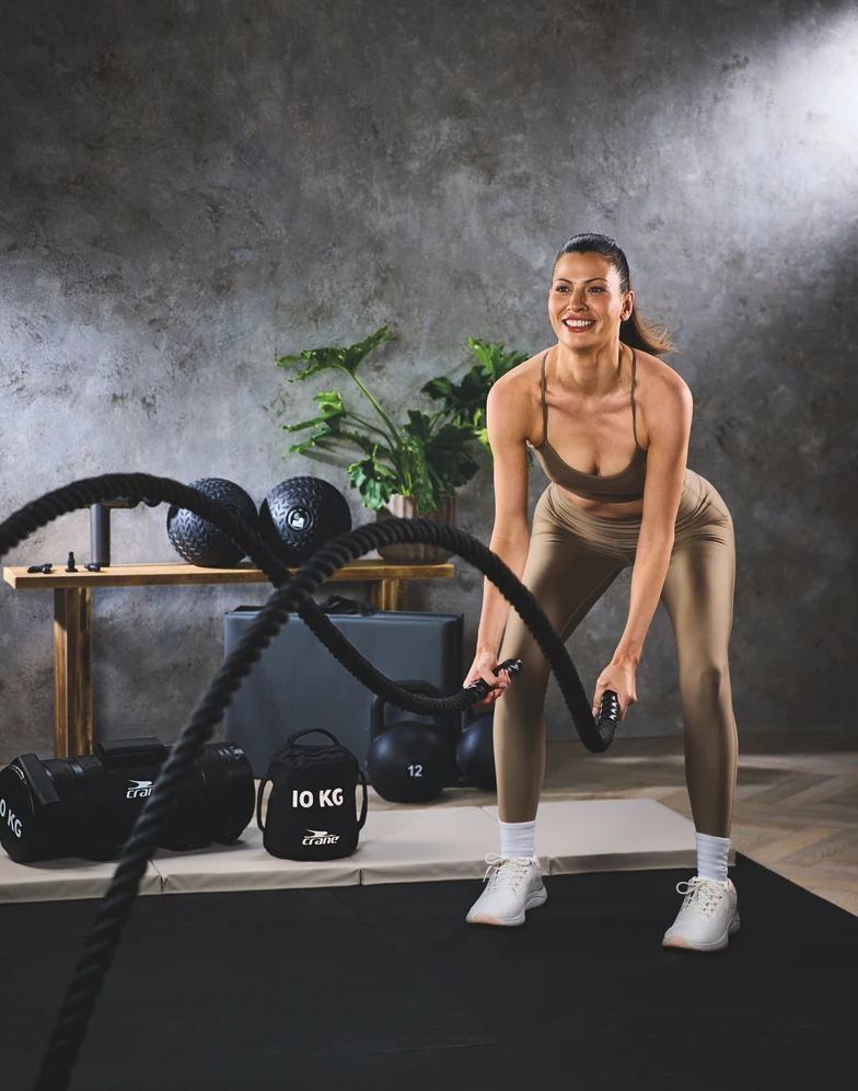 Woman training with Aldi Crane 12m battle ropes at home gym.