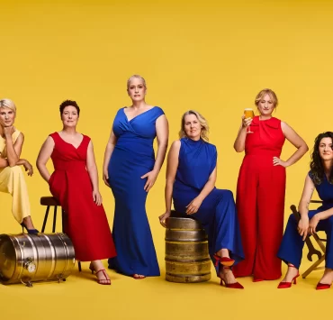 Six women brewers from Scotland pose in bold red, blue and yellow outfits with beer barrels and glasses, marking Lidl’s gender-balanced beer aisle initiative.