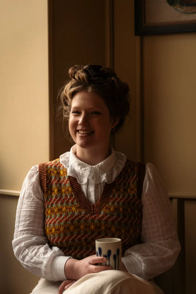 Darcie Maher, founder of Lannan Bakery, smiling indoors with a ceramic mug