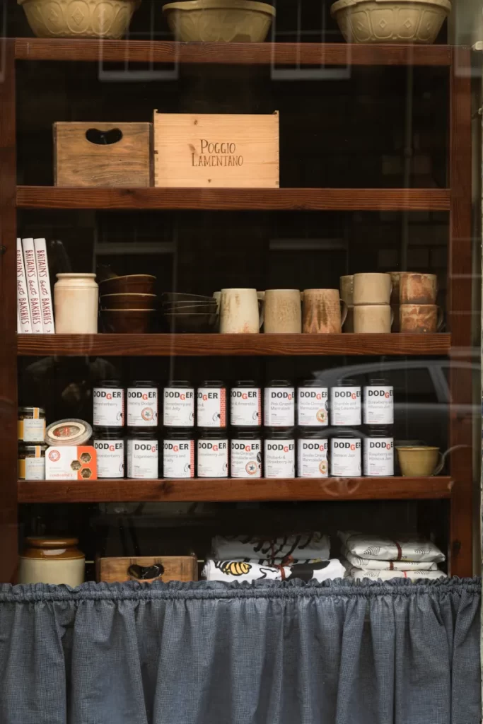 Pantry window with jars of Dodger jam, handmade mugs and baking bowls