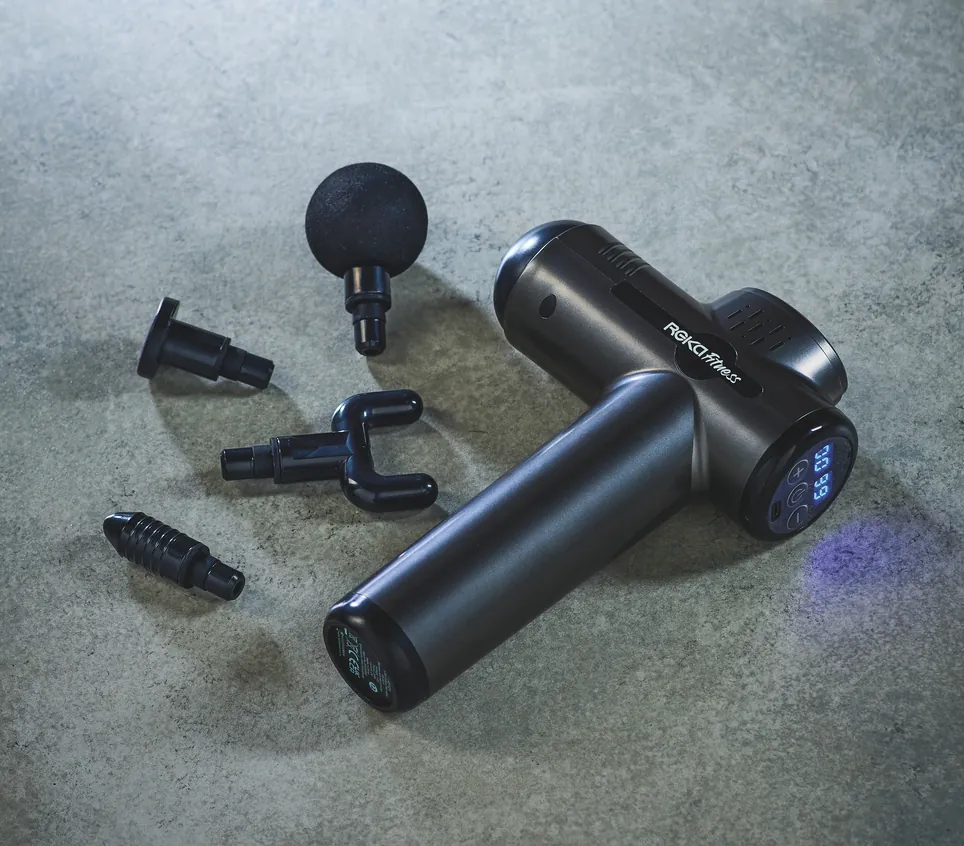 Aldi Crane massage gun with four massage head attachments on a grey surface.