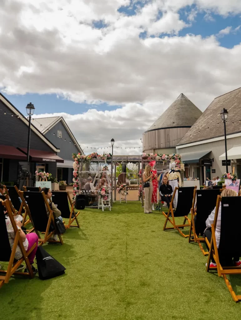 Audience seated in deck chairs watching stage at Caledonia Park designer outlet, Gretna Green.