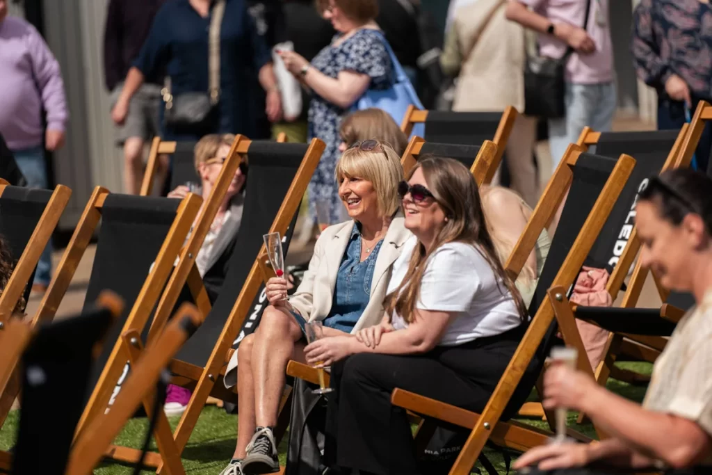 Women enjoying fizz in deck chairs at Caledonia Park outlet shopping village, Gretna Green.
