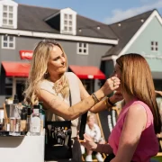 Make-up artist applying products to guest at Caledonia Park designer outlet shopping village, Gretna Green.