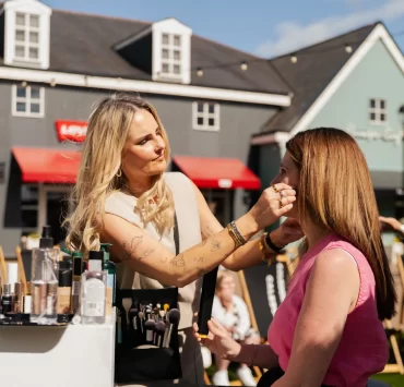 Make-up artist applying products to guest at Caledonia Park designer outlet shopping village, Gretna Green.