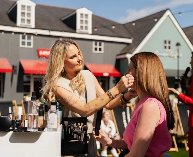 Make-up artist applying products to guest at Caledonia Park designer outlet shopping village, Gretna Green.