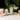 Five cocktails in different glasses on a terrazzo table, including a pink spritz, a short glass with melon garnish, a tall mojito-style drink, a pink martini and a golden cocktail rimmed with spice.