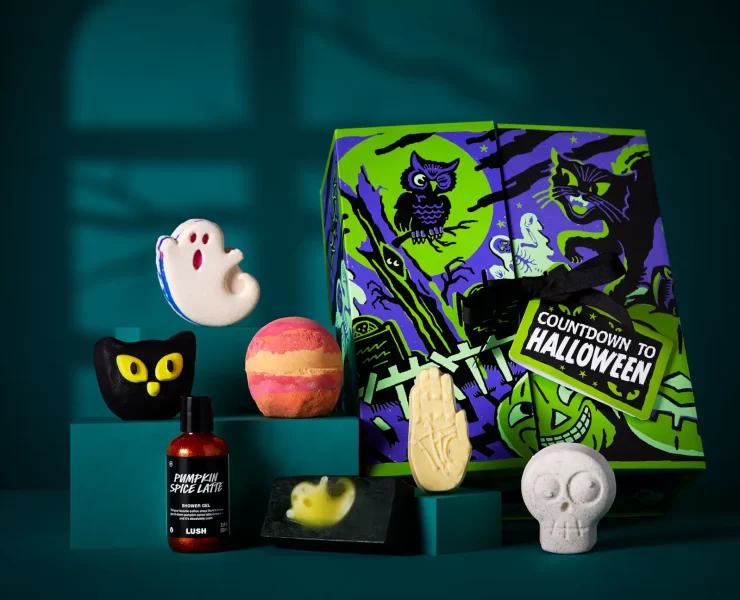 Lush Countdown to Halloween advent calendar box with seven products – including ghost and skeleton bath bombs, Pumpkin Spice Latte shower gel and spooky soap – displayed against a dark teal background.