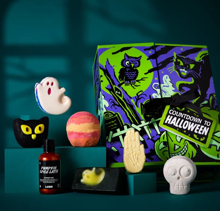 Lush Countdown to Halloween advent calendar box with seven products – including ghost and skeleton bath bombs, Pumpkin Spice Latte shower gel and spooky soap – displayed against a dark teal background.