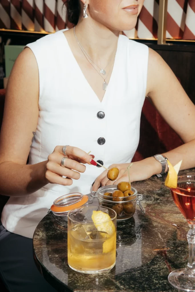 Woman enjoying cocktails and olives at The Delphine, a chic new cocktail bar in Glasgow’s Princes Square.