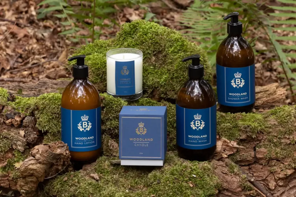 Balmoral Estate Woodland Range by Laura Thomas Co — natural hand wash, hand lotion, shower wash and candle displayed on moss-covered woodland ground.