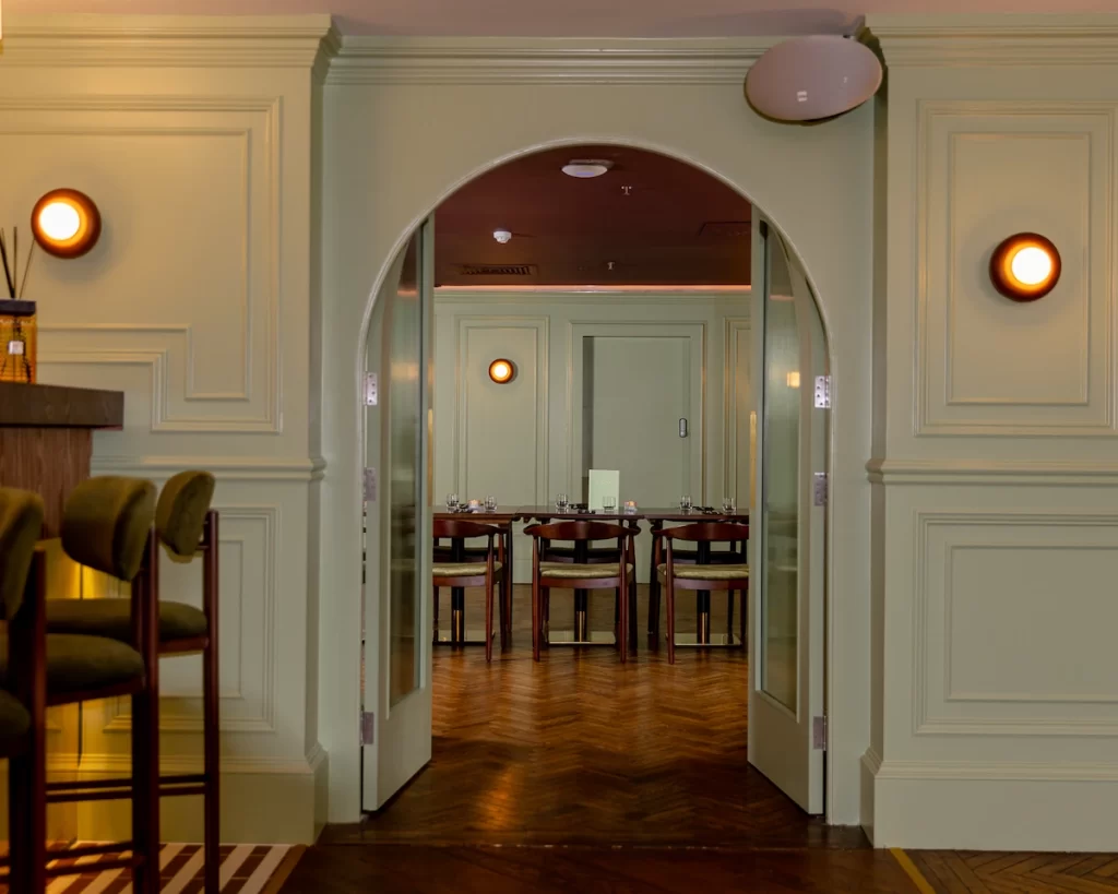 Interior of The Delphine cocktail and wine bar in Princes Square, Glasgow, with chic green walls and modern design.