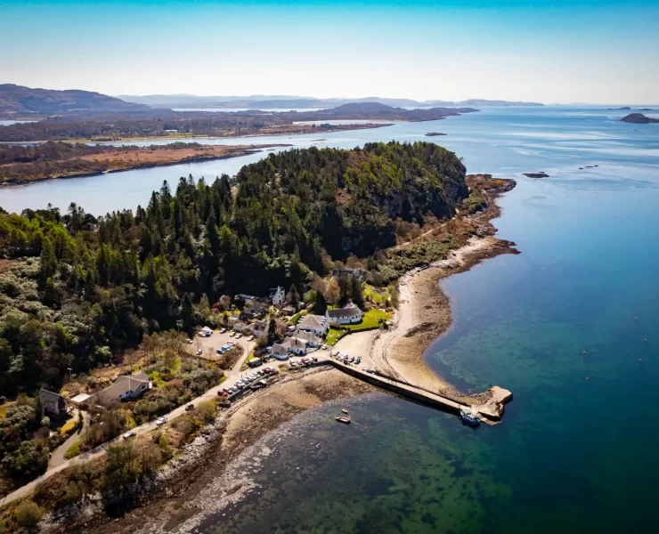 Aerial photograph of The Pierhouse Hotel and Seafood Restaurant in Port Appin, Argyll, surrounded by woodland and overlooking the blue waters of Loch Linnhe.