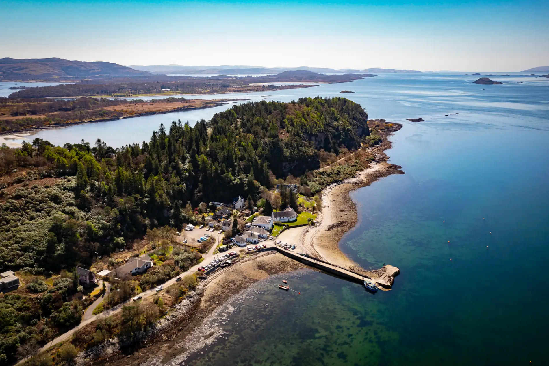 Aerial photograph of The Pierhouse Hotel and Seafood Restaurant in Port Appin, Argyll, surrounded by woodland and overlooking the blue waters of Loch Linnhe.