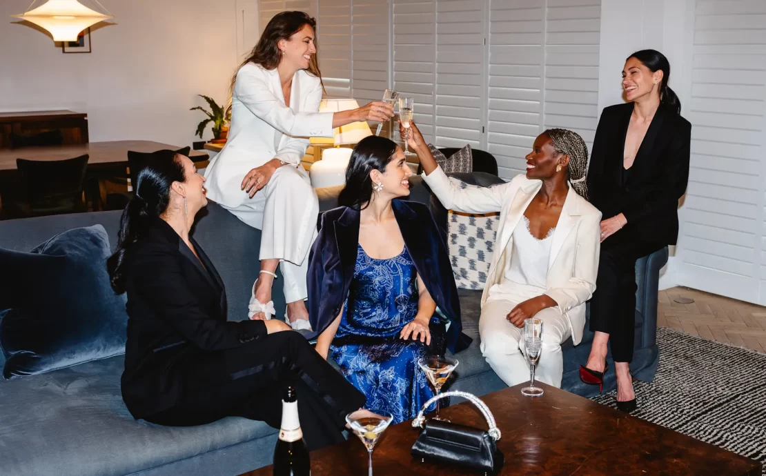 Group of women dressed in Gormley & Gamble tailored suits raising champagne glasses in celebration at Gleneagles Townhouse Edinburgh