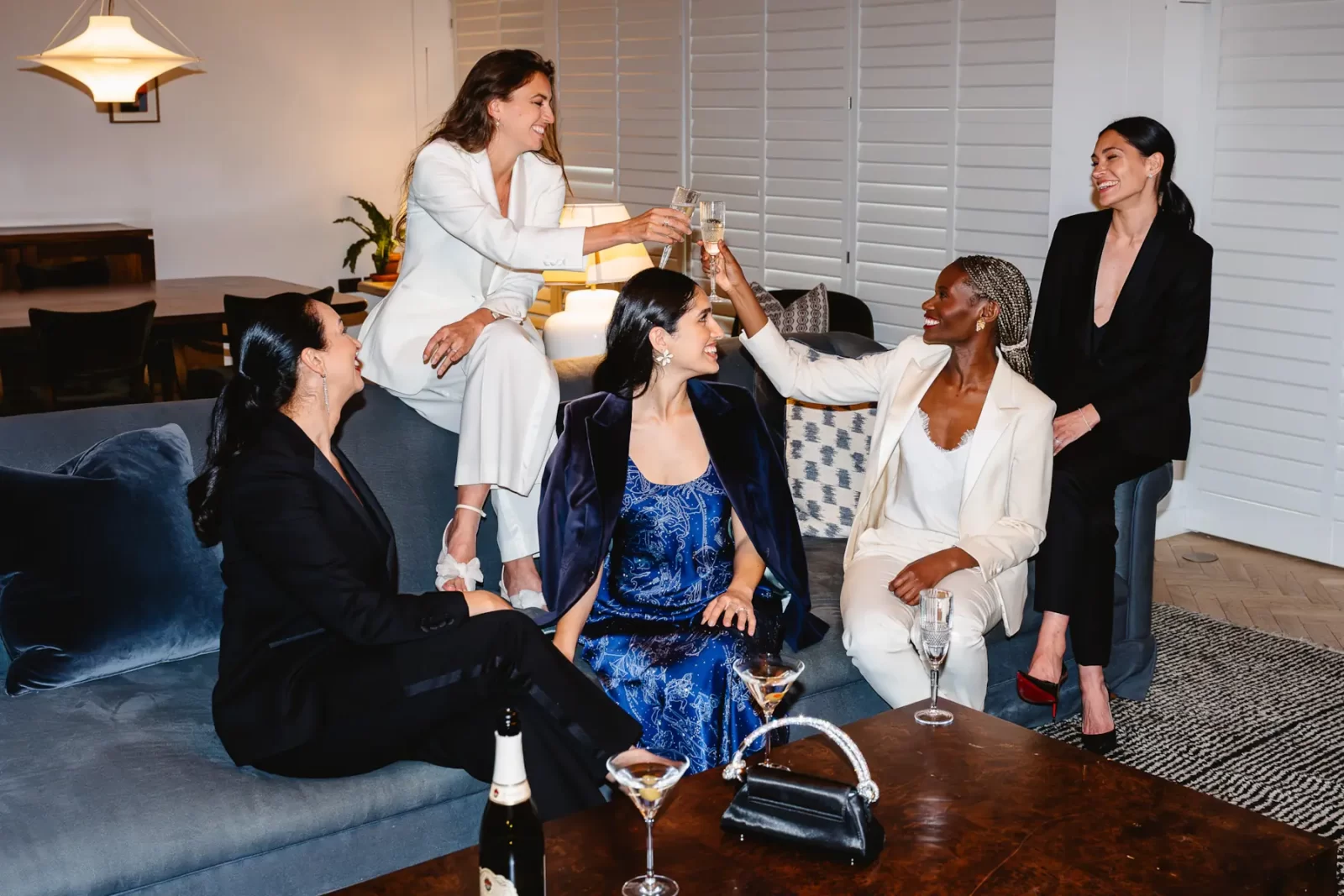 Group of women dressed in Gormley & Gamble tailored suits raising champagne glasses in celebration at Gleneagles Townhouse Edinburgh