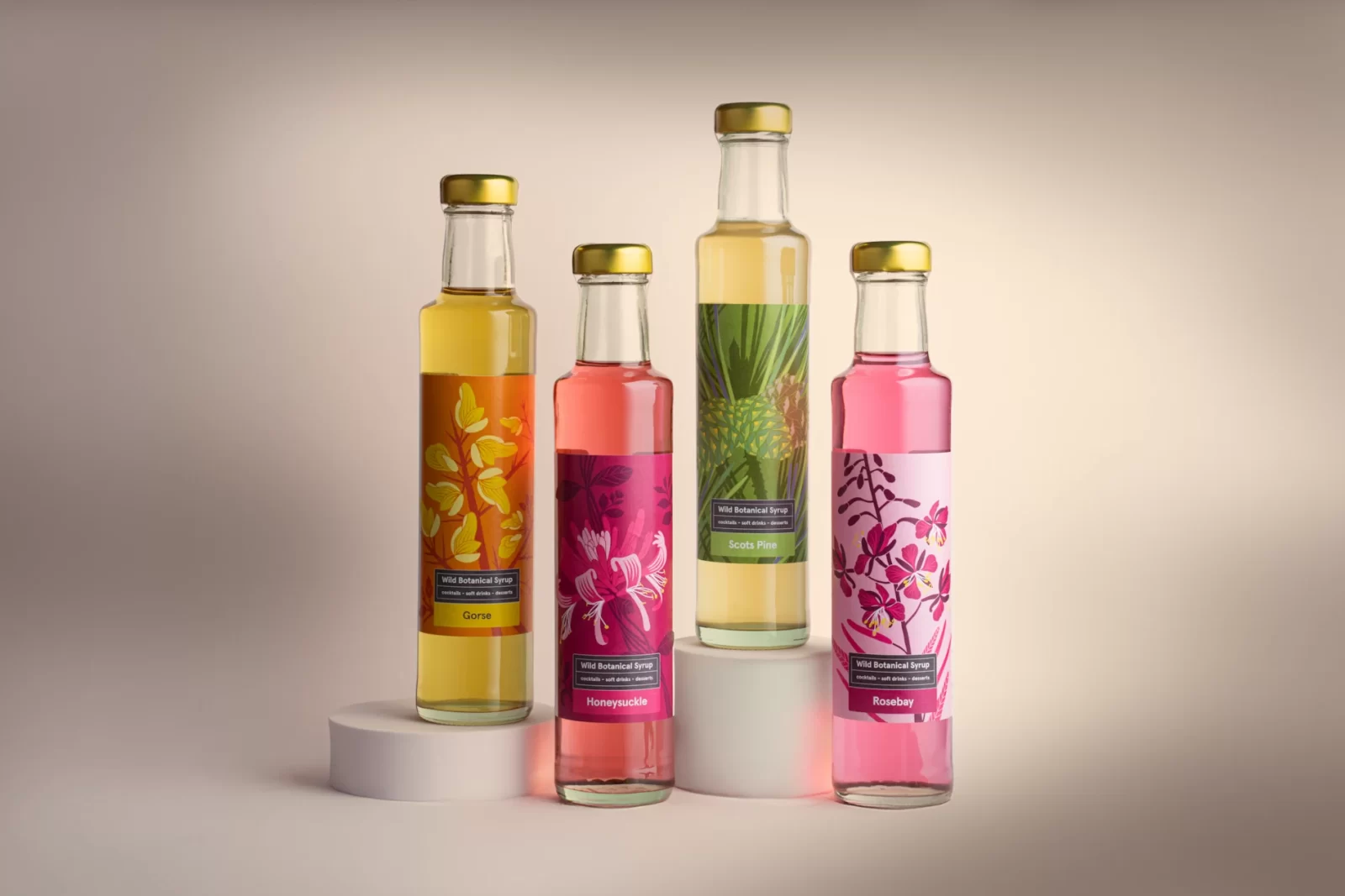Four glass bottles of Highland Boundary Wild Botanical Syrups in vibrant packaging — Gorse, Honeysuckle, Scots Pine and Rosebay — photographed against a soft neutral background.