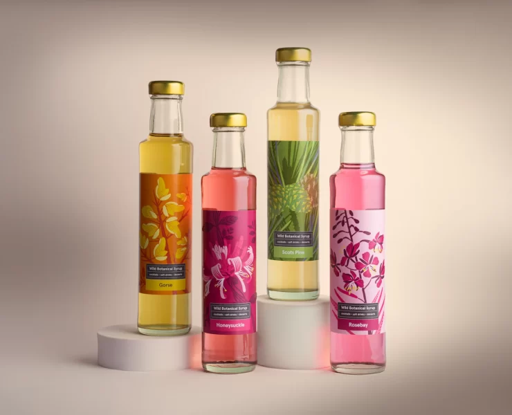 Four glass bottles of Highland Boundary Wild Botanical Syrups in vibrant packaging — Gorse, Honeysuckle, Scots Pine and Rosebay — photographed against a soft neutral background.