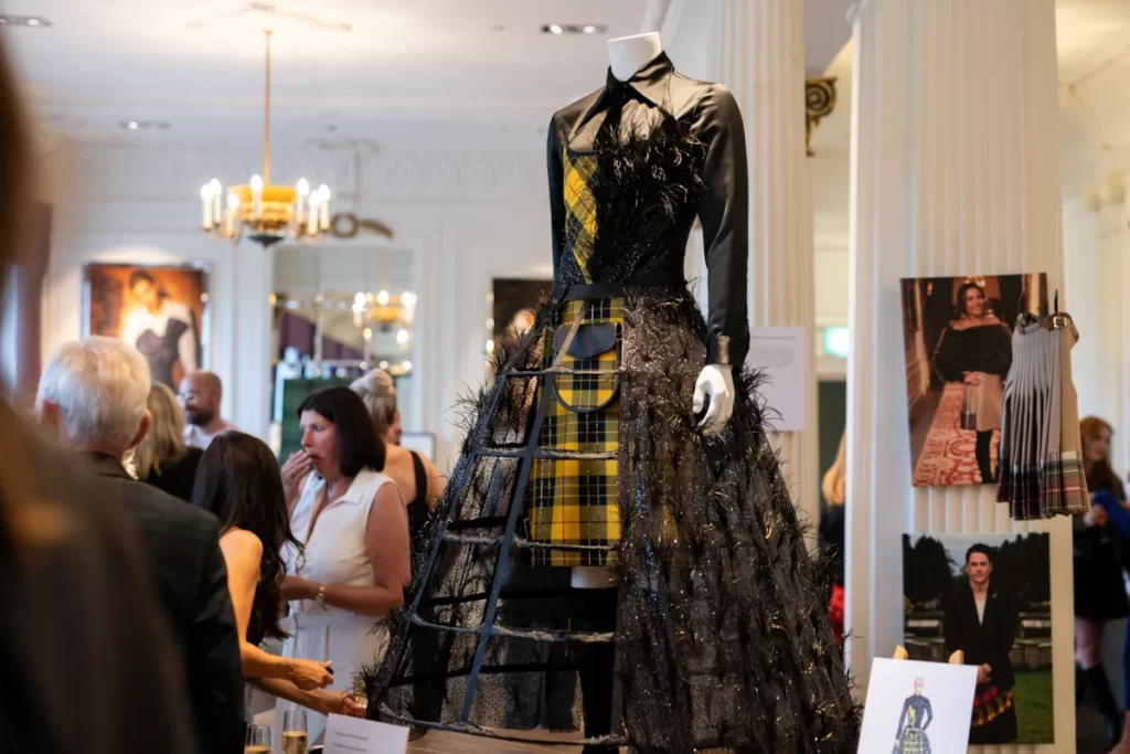 A mannequin wearing a black and yellow tartan gown displayed in an exhibition room surrounded by guests at Blythswood Square Hotel